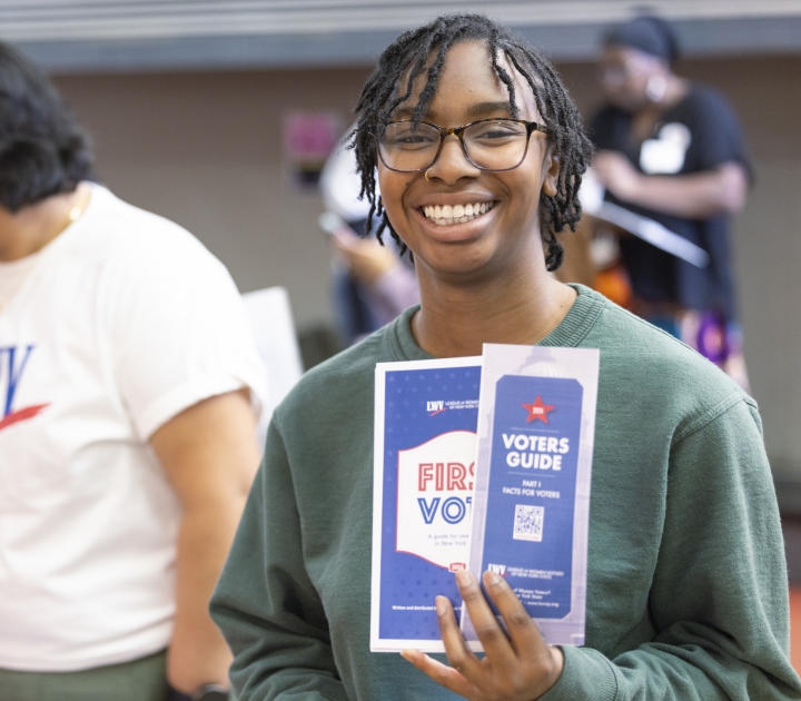 Smiling student holding voter registration and voting guides