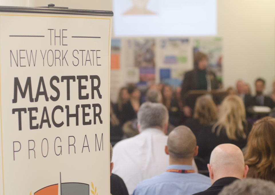 A sign that reads The New York State  Master Teacher Program next to a group of people 